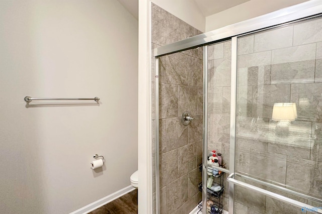 bathroom featuring hardwood / wood-style floors, a shower with door, and toilet