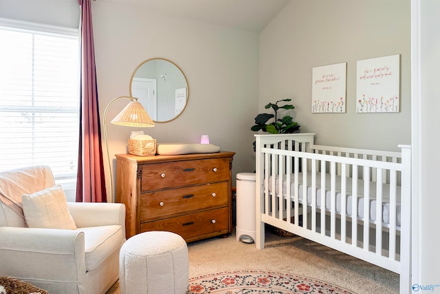 carpeted bedroom with lofted ceiling and a crib