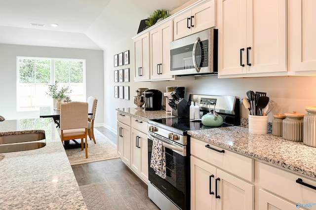 kitchen with white cabinets, light stone countertops, dark hardwood / wood-style flooring, stainless steel appliances, and lofted ceiling