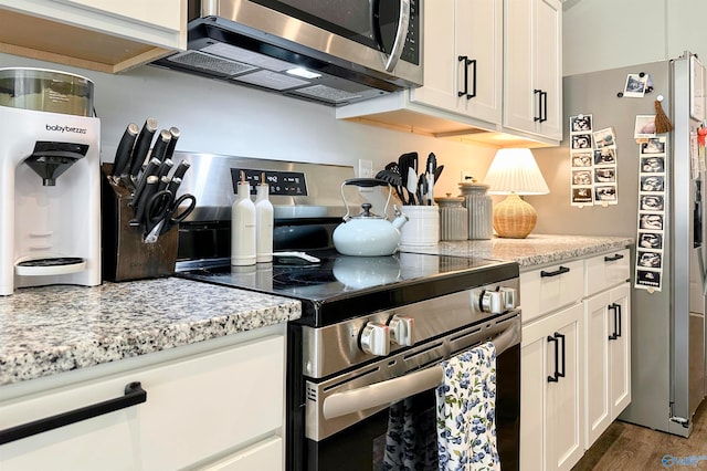 kitchen featuring white cabinets, appliances with stainless steel finishes, dark hardwood / wood-style flooring, and light stone countertops