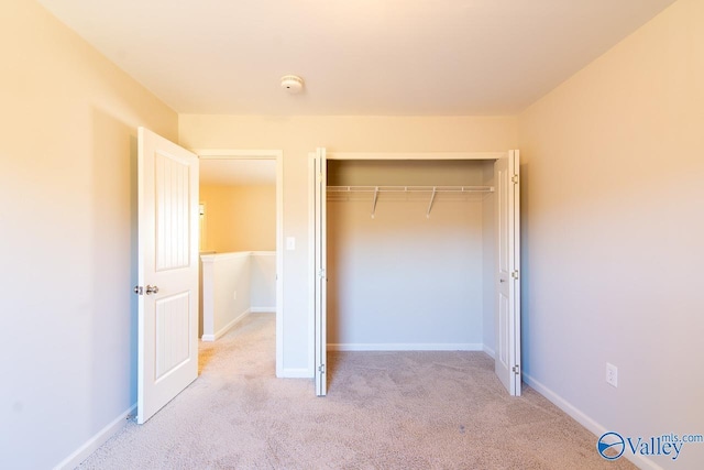 unfurnished bedroom with light colored carpet and a closet