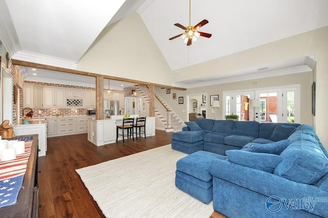 living area with a ceiling fan, dark wood-style flooring, stairway, high vaulted ceiling, and ornamental molding