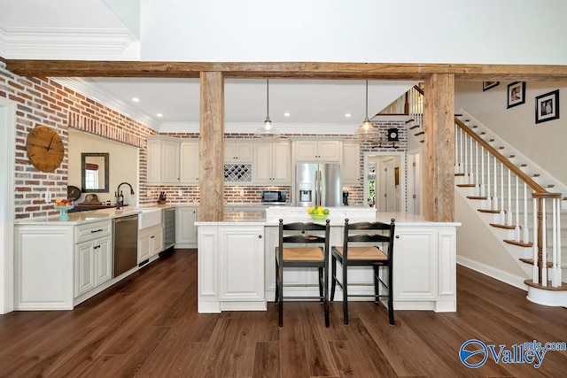 kitchen featuring crown molding, appliances with stainless steel finishes, a kitchen breakfast bar, and dark wood-type flooring