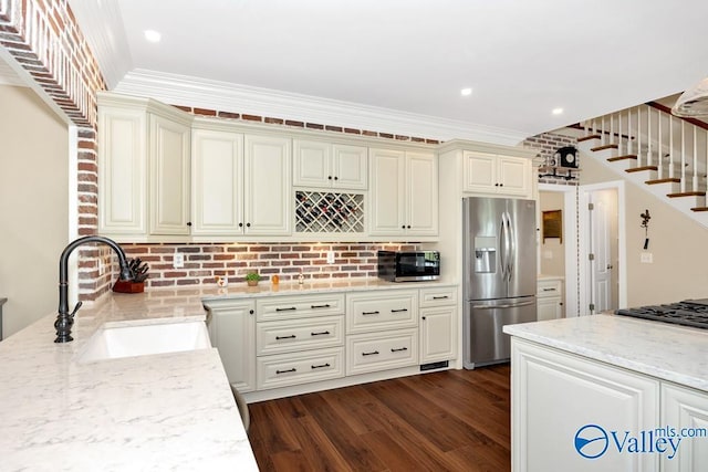 kitchen with dark wood-style flooring, crown molding, light stone countertops, a sink, and stainless steel appliances
