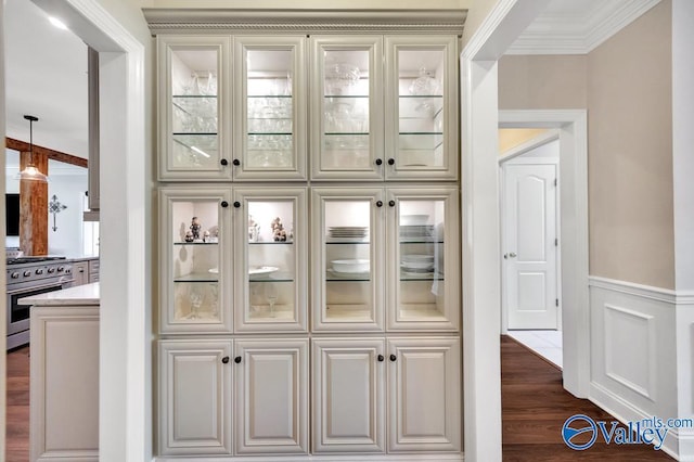 bar featuring crown molding, dark wood finished floors, high end stainless steel range, and a wainscoted wall