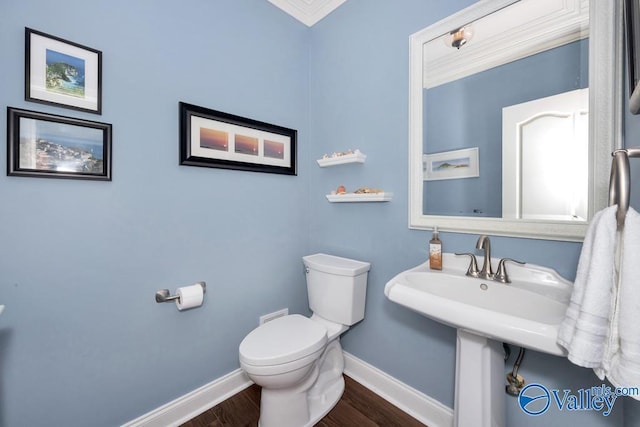 bathroom featuring crown molding, baseboards, toilet, and wood finished floors