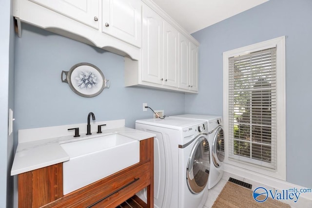 laundry area featuring visible vents, separate washer and dryer, a sink, cabinet space, and light tile patterned floors
