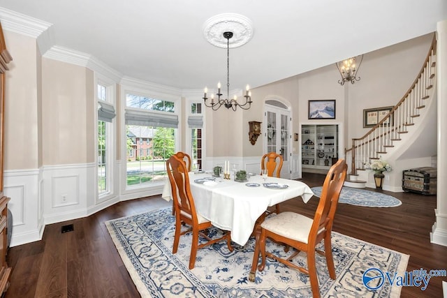 dining room with an inviting chandelier, a wainscoted wall, stairs, and wood finished floors