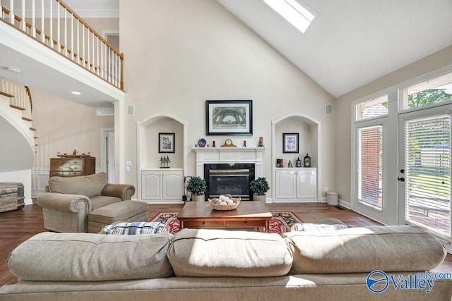 living room featuring visible vents, wood finished floors, a fireplace, high vaulted ceiling, and a skylight