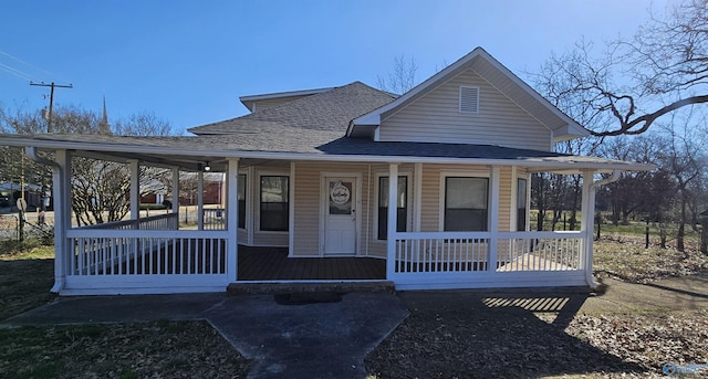 view of front facade with a shingled roof and a porch