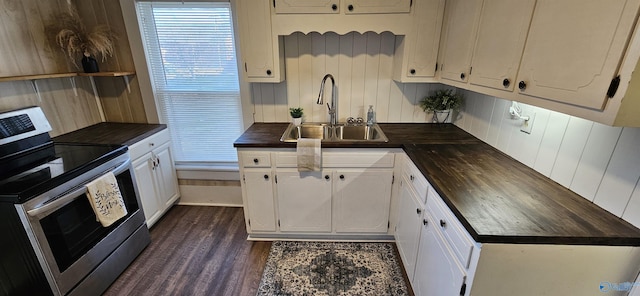 kitchen featuring butcher block counters, dark wood-type flooring, stainless steel electric range, white cabinetry, and a sink