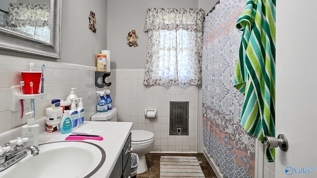 bathroom with curtained shower, toilet, vanity, wainscoting, and tile walls