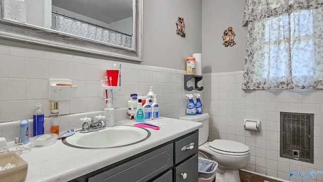 full bath with heating unit, toilet, vanity, and tile walls