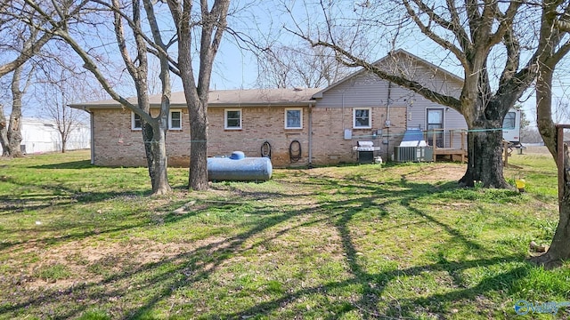 back of property with a yard and brick siding