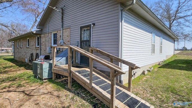 exterior space with a yard, cooling unit, and brick siding