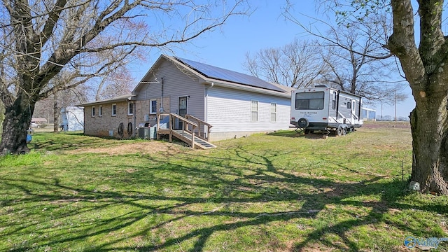 view of home's exterior with a yard, solar panels, central AC, and metal roof