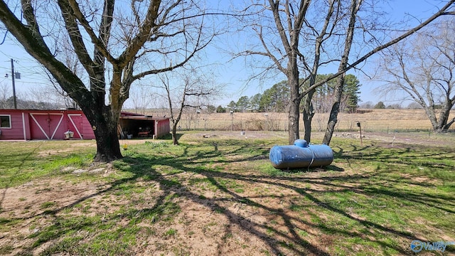 view of yard with a rural view, a barn, and an outdoor structure