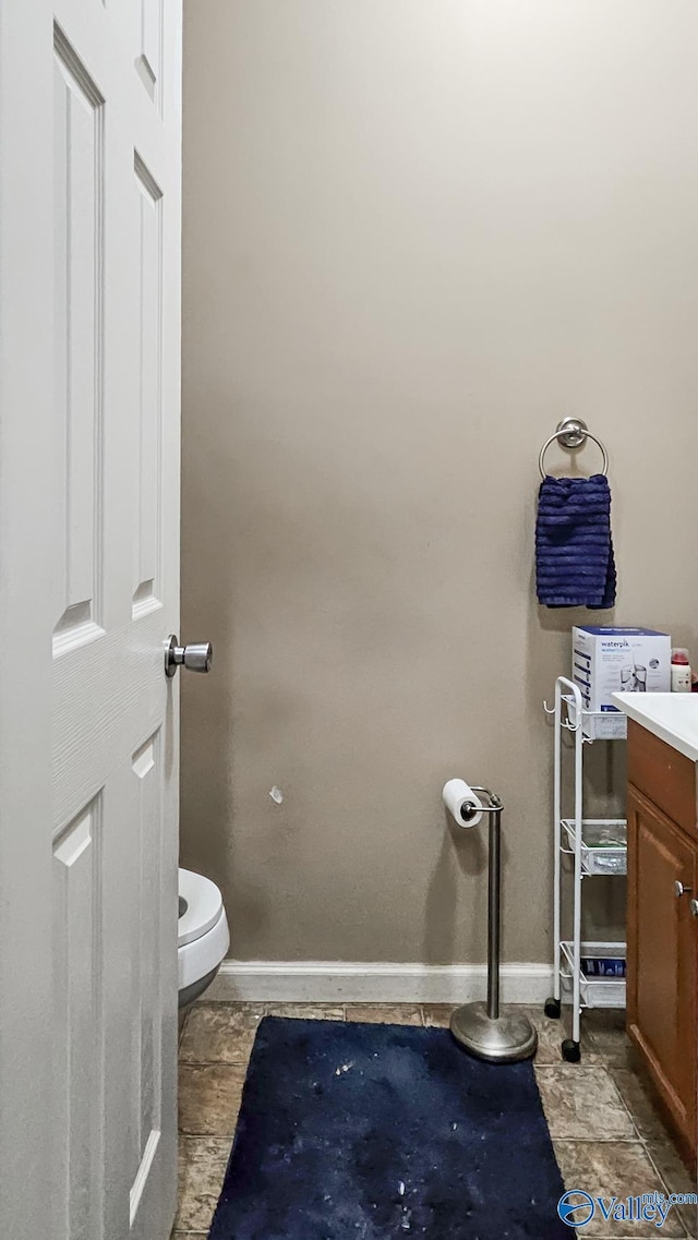 half bath featuring vanity, toilet, and baseboards