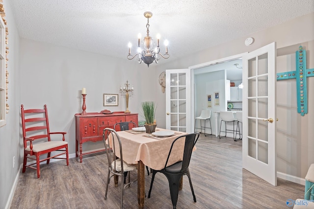 dining area featuring french doors, hardwood / wood-style flooring, an inviting chandelier, and a textured ceiling