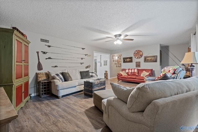 living room featuring dark wood-type flooring, ceiling fan, and a textured ceiling