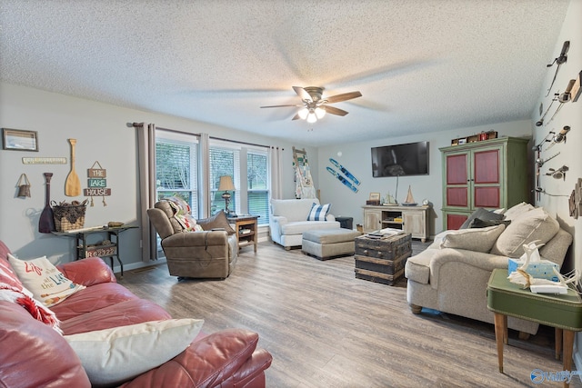 living room featuring light wood-type flooring, ceiling fan, and a textured ceiling