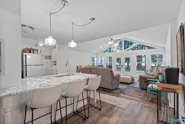 kitchen with white fridge, vaulted ceiling, a wealth of natural light, and sink