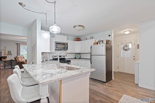 kitchen with kitchen peninsula, appliances with stainless steel finishes, wood-type flooring, and white cabinetry