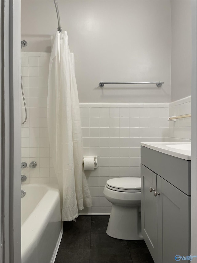 full bathroom with shower / bath combo, tile walls, vanity, tile patterned floors, and toilet