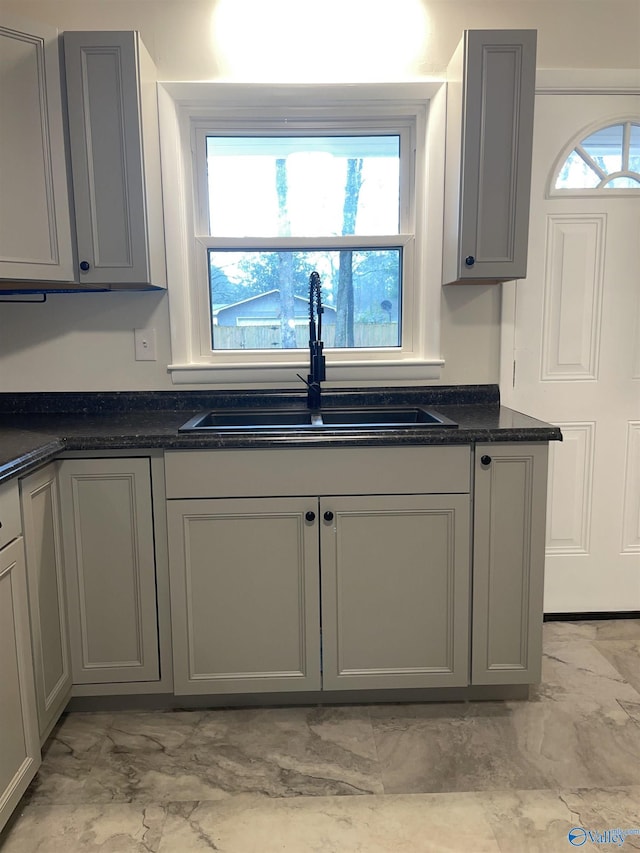 kitchen featuring gray cabinets, sink, and dark stone countertops