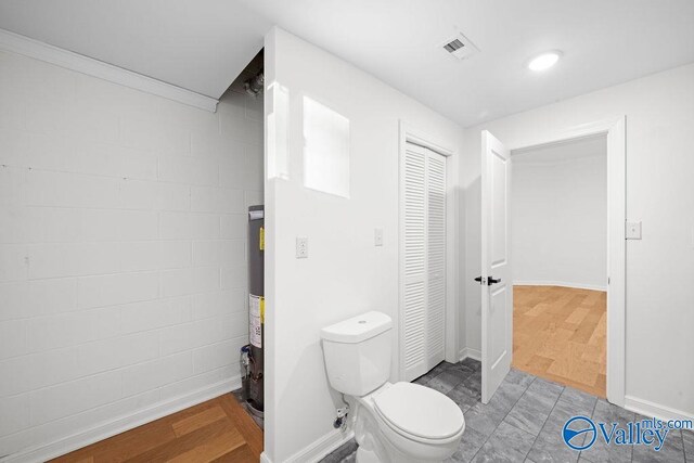 bathroom featuring hardwood / wood-style flooring, toilet, and gas water heater