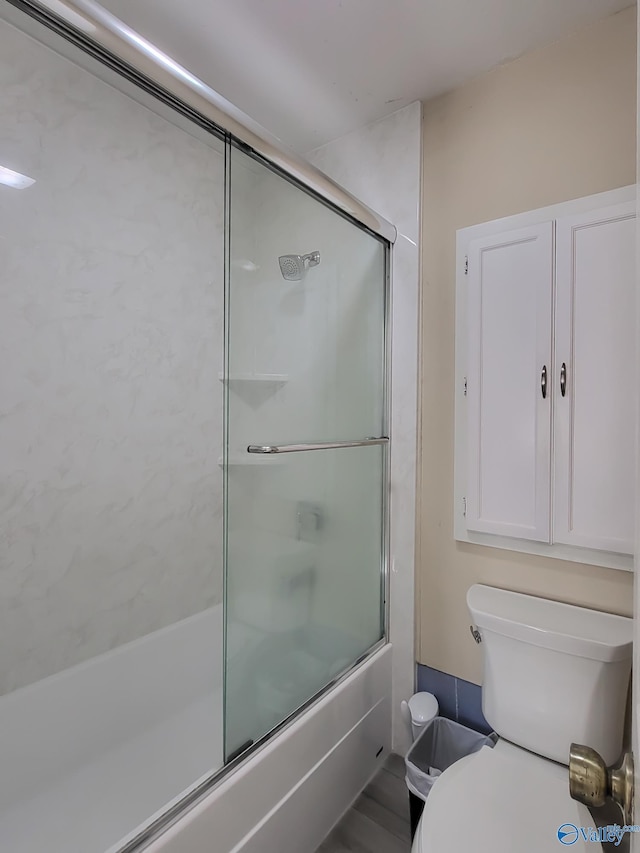 bathroom with combined bath / shower with glass door and toilet