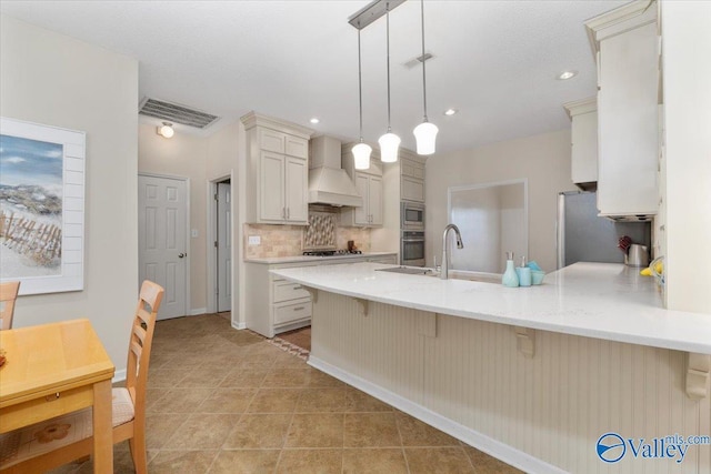 kitchen featuring hanging light fixtures, stainless steel appliances, custom range hood, a breakfast bar, and backsplash