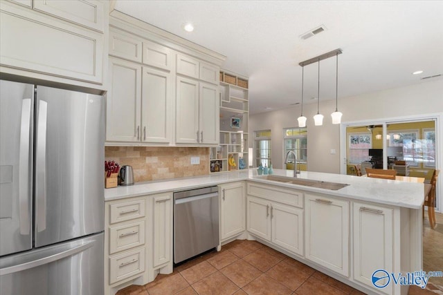 kitchen featuring sink, kitchen peninsula, decorative backsplash, pendant lighting, and appliances with stainless steel finishes