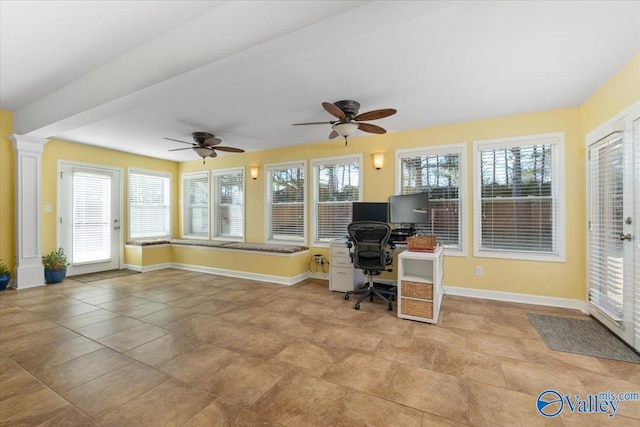 unfurnished office featuring ceiling fan, a wealth of natural light, and decorative columns