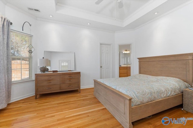 bedroom featuring ensuite bath, ceiling fan, light hardwood / wood-style floors, and a raised ceiling