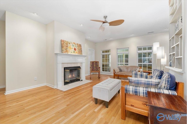 living room with light hardwood / wood-style floors, ceiling fan, and a tile fireplace