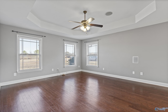 empty room featuring ceiling fan, dark hardwood / wood-style flooring, and a tray ceiling