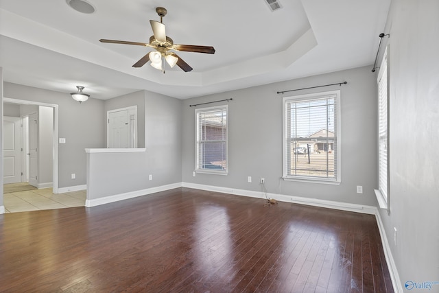 unfurnished room featuring ceiling fan, a tray ceiling, and light hardwood / wood-style flooring