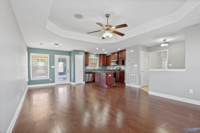 kitchen featuring appliances with stainless steel finishes, dark hardwood / wood-style flooring, a tray ceiling, and a center island