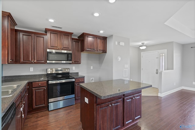 kitchen with sink, appliances with stainless steel finishes, dark hardwood / wood-style flooring, and a center island