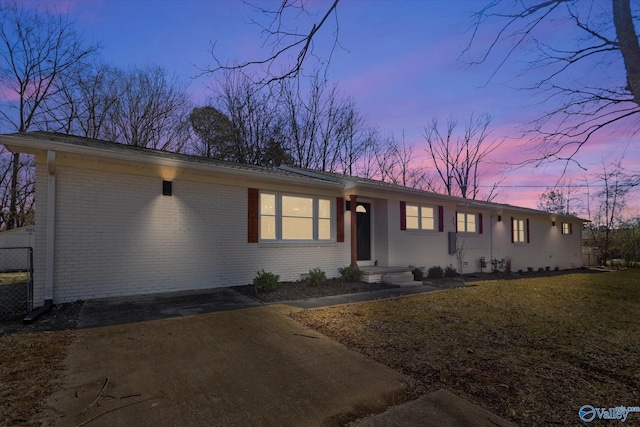 view of front of property with fence, a lawn, and brick siding