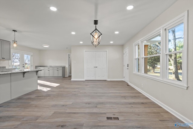 unfurnished dining area with light wood-style floors, baseboards, visible vents, and recessed lighting