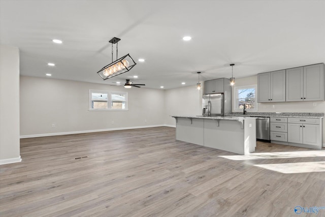 kitchen featuring open floor plan, stainless steel appliances, gray cabinetry, light wood-type flooring, and recessed lighting