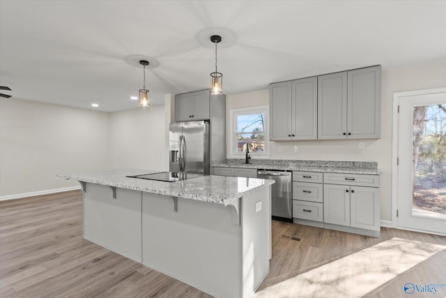 kitchen featuring light wood-style floors, appliances with stainless steel finishes, a wealth of natural light, and gray cabinetry