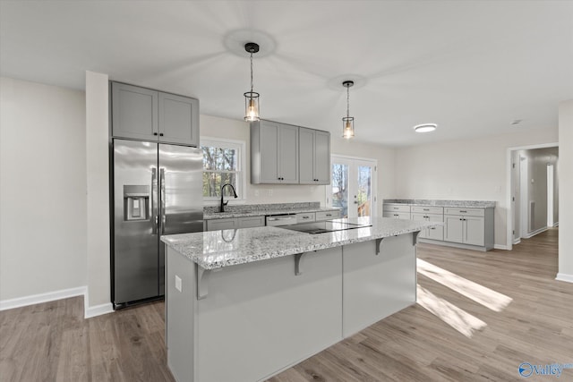 kitchen featuring black electric stovetop, gray cabinets, light wood-style floors, a sink, and stainless steel fridge