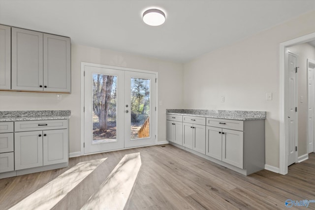 interior space featuring light wood-type flooring, baseboards, and french doors