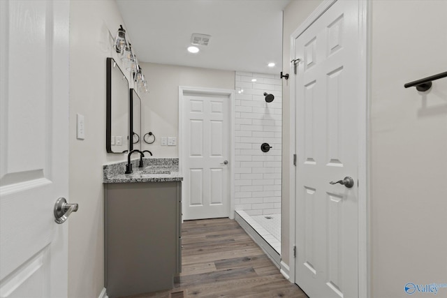 bathroom featuring visible vents, tiled shower, wood finished floors, vanity, and recessed lighting