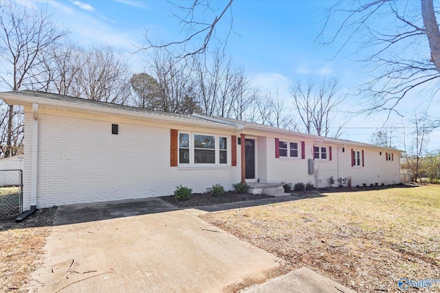 single story home with driveway, brick siding, a front lawn, and fence