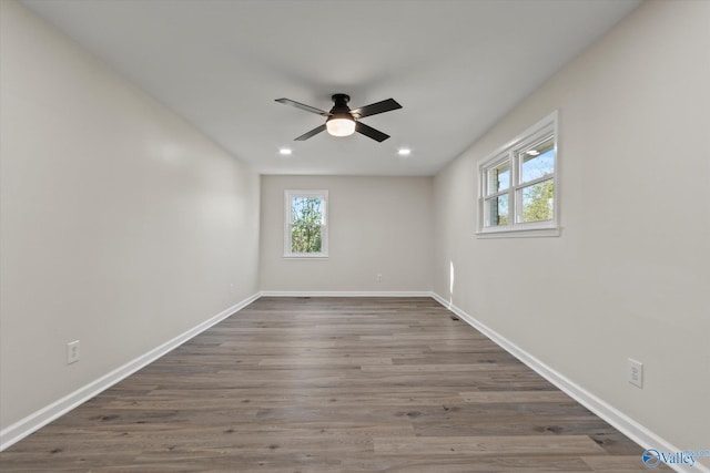 spare room featuring a ceiling fan, a wealth of natural light, baseboards, and wood finished floors