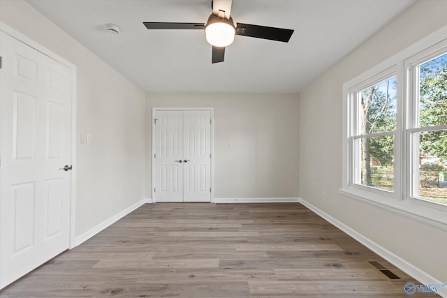 empty room featuring light wood-style floors, a healthy amount of sunlight, visible vents, and baseboards